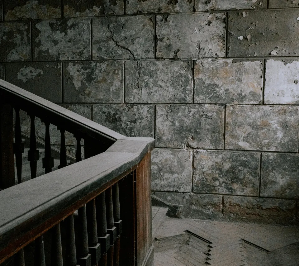 Escalier en bois recouvert de poussière blanche près d'un mur de béton gris