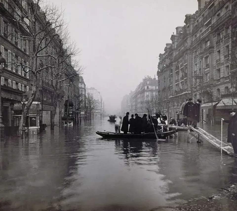 Image de la Crue de 1910. Prise de vue d'un boulevard. On y voit des personnes sur une barque pour traverser la rue.